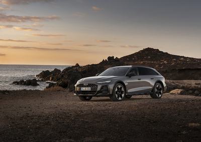Audi A6 allroad (pearl grey) in side view at a rugged coastal landscape during sunset.
