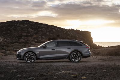 Side silhouette of the Audi A6 allroad (pearl grey) at low sun along a rugged coastline.