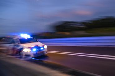 Dutch police car rushing to the scene of an incident near the city of Kampen at night. The car is driving with sirens and flashlights at high speed.