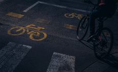 Unrecognisable person riding his bicycle along a cycle lane. In the picture we can see several drawings of a bicycle, painted on the road to indicate a bicycle lane. Image taken in the city of Budapest.