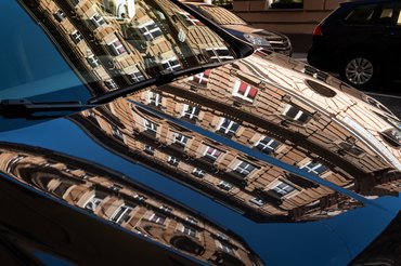 reflection of buildings on black car standing on a street in Vienna, Austria