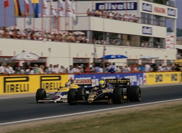Ayrton Senna from Brazil driving the #12 John Player Special Team Lotus-Renault 98T Renault V6 and Nigel Mansell from Great Britain driving the #5 Canon Williams Honda Williams FW11 Honda V6 race down the front straight side by side during the Formula One Hungarian Grand Prix on 10th August 1986 at the Hungaroring Circuit, Budapest, Hungary. (Photo by Mike King/Allsport/Getty Images)