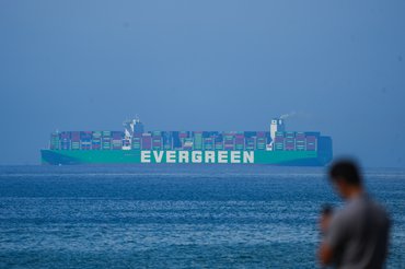 A man is taking a picture of an Evergreen container ship in Colombo, Sri Lanka, on February 1, 2024. (Photo by Thilina Kaluthotage/NurPhoto via Getty Images)