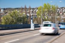 Blurry cares driving by a gray, mobile, car traffic speed trap camera between two car lane. Close up, telephoto shot.