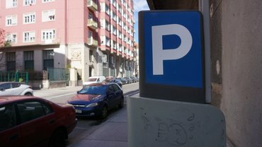 Budapest, Hungary 08-03-2025. Blue parking sign stands on a city street. Residential buildings and parked cars in the background. Urban planning, parking tariffs, limited parking space.