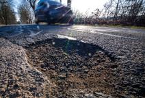 PRODUCTION - 09 March 2026, Mecklenburg-Western Pomerania, Lützow: A car drives past a pothole in a district road. Prolonged frost and repeated freeze/thaw cycles have taken their toll on the roads in Mecklenburg-Vorpommern. Photo: Jens Büttner/dpa (Photo by Jens Büttner/picture alliance via Getty Images)