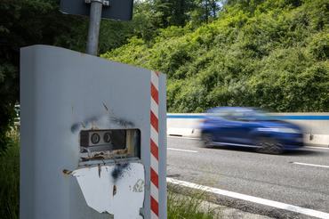 Speed camera beside road with motion blurred car passing at high speed in traffic control and road safety concept