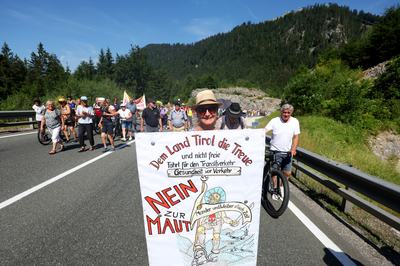 27 June 2026, Austria, Reutte: A protester holding a sign that reads "No to the Toll" is marching in a demonstration procession along the closed B179 Fernpass Road toward a rally. Photo: Karl-Josef Hildenbrand/dpa (Photo by Karl-Josef Hildenbrand/picture alliance via Getty Images)