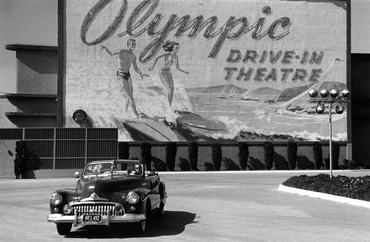 28th April 1951:  A couple in an open-top car driving past a sign advertising Hollywood's Olympic drive-in theatre in Los Angeles, California.  Original Publication: Picture Post - 5298 - Two Men In Hollywood - pub. 1951  (Photo by Kurt Hutton/Picture Post/Hulton Archive/Getty Images)