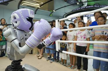 ZHENGZHOU, CHINA - JUNE 01: Children watch a boxing robot performance at a humanoid robot experience center on June 1, 2026 in Zhengzhou, Henan Province of China. Parents brought children to visit an humanoid robot experience center on International Children's Day. (Photo by Fan Xiaoheng/China News Service/VCG via Getty Images)